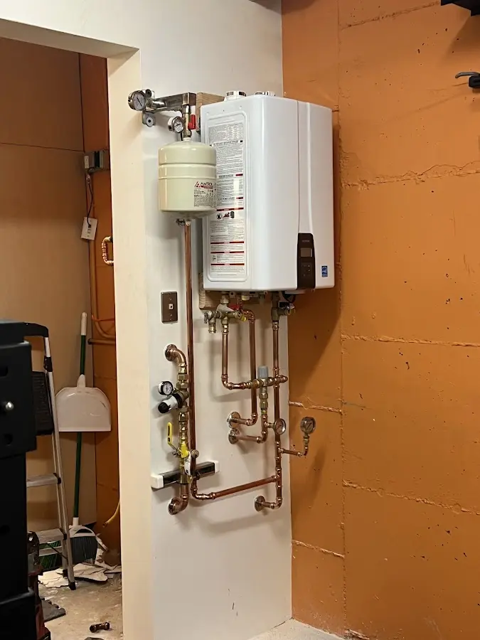 Plumbing technician inspecting water heater connections in Rose
